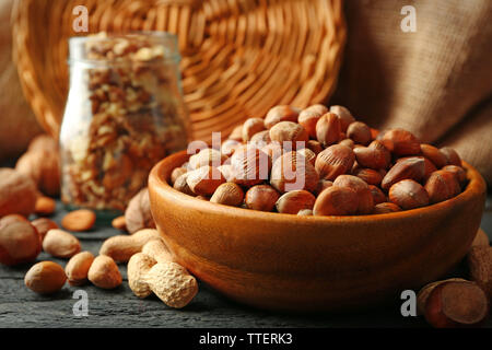 Haselnüsse, Walnüsse, Erdnüsse in der Schale und Glas auf dem Tisch Stockfoto