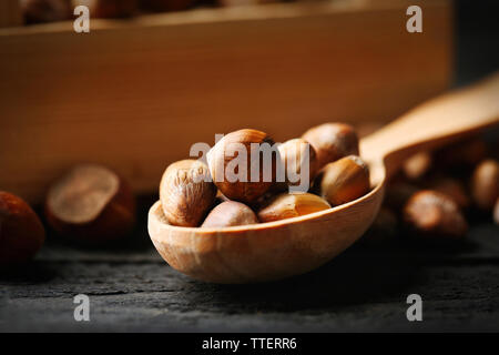 Haselnüsse in der Holzkiste und Löffel auf dem Tisch, Nahaufnahme Stockfoto