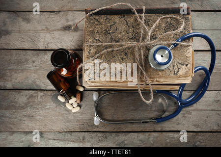 Stapel von Büchern, Pillen und Stethoskop auf Holztisch, Ansicht von oben Stockfoto