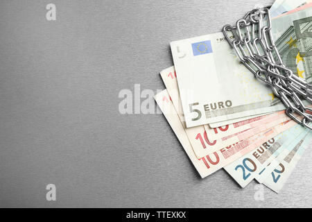 Euro-banknoten mit Schloss und Kette auf grauem Hintergrund Stockfoto