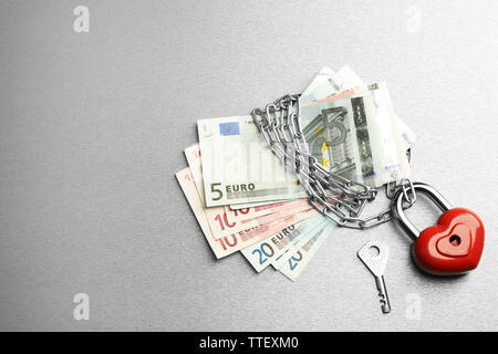 Euro-banknoten mit Schloss und Kette auf grauem Hintergrund Stockfoto