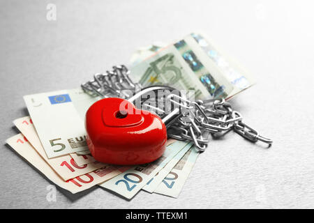 Euro-banknoten mit Schloss und Kette auf grauem Hintergrund Stockfoto