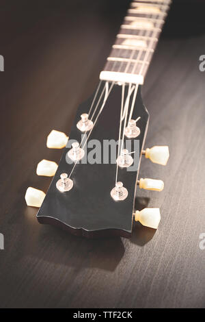 Kopf der E-Gitarre mit stimmwirbel auf schwarzem Holz- Hintergrund Stockfoto