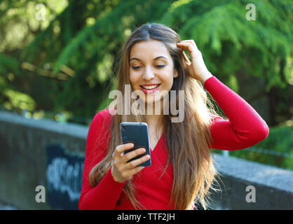 Überrascht junge Frau mit Smart Phone im Freien. Urban Mädchen mit im City Park neues Mobiltelefon app aufgeregt. Stockfoto