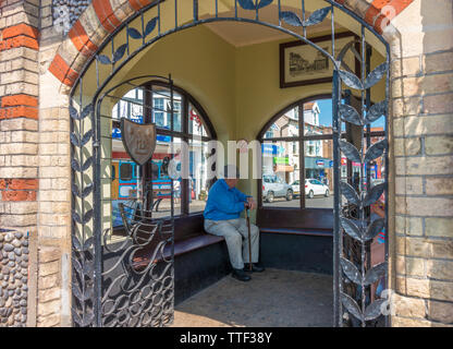 Alter Mann in Sheringham Town Center vermeiden die Hitze an einem heißen Sommer Tag, innerhalb der historischen Uhr Gebäude von 1862. North Norfolk, England, UK. Stockfoto