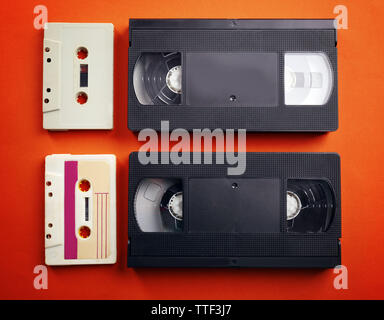 Satz von alten Audio- und Videokassetten auf rotem Hintergrund Stockfoto