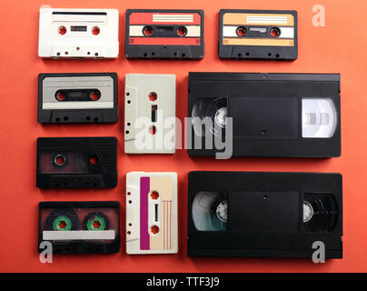 Satz von alten Audio- und Videokassetten auf rotem Hintergrund Stockfoto