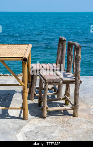 Bambus Tisch und Stühle aus Holz in leeren Cafe neben Meer Wasser in tropischen Strand. Close Up. Insel Koh Phangan, Thailand Stockfoto