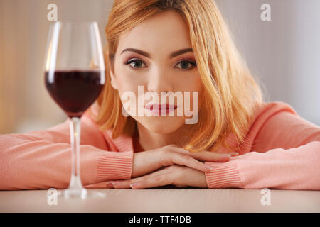 Junge Frau mit einem Glas Rotwein auf dem leicht verschwommenen Hintergrund Stockfoto
