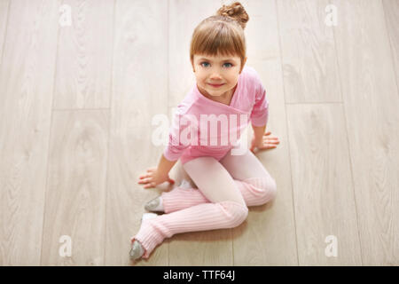 Kleine süße Mädchen in rosa Body sitzen auf dem Boden im Tanzstudio Stockfoto