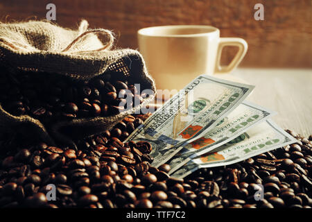 Kaffeebohnen, Tasse und US Dollar Banknoten auf hölzernen Hintergrund Stockfoto