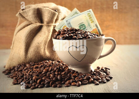 Kaffeebohnen, Tasse und US Dollar Banknoten auf hölzernen Hintergrund Stockfoto