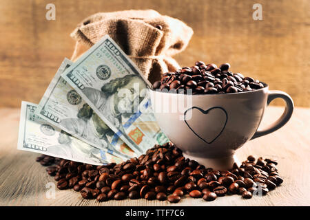 Kaffeebohnen, Tasse und US Dollar Banknoten auf hölzernen Hintergrund Stockfoto
