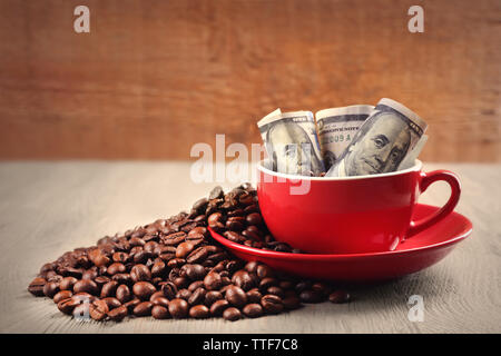Kaffeebohnen, Tasse und US Dollar Banknoten auf hölzernen Hintergrund Stockfoto