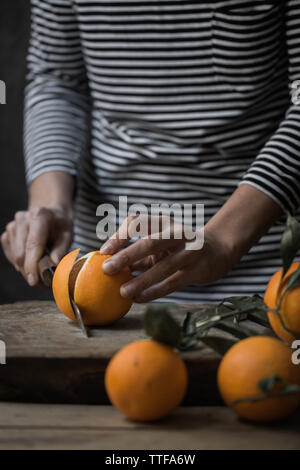 Junge Frau Schneiden frische Orange Scheiben Stockfoto