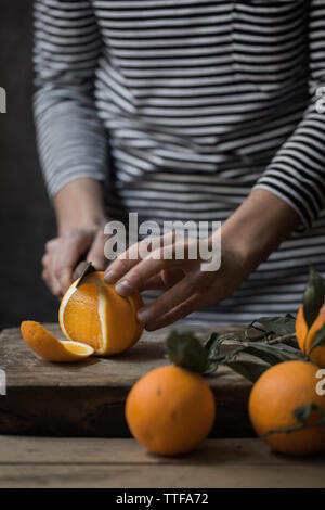 Junge Frau Schneiden frische Orange Scheiben Stockfoto