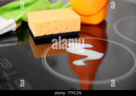 Reinigungsmittel mit Schutzhandschuhe und Schwamm auf Elektroherd closeup Stockfoto