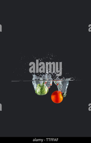 Cherry Tomaten und Brussel Spritzwasser über einen dunklen Hintergrund keimen Stockfoto