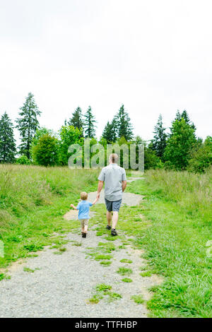 Rückansicht eines Vater und Sohn einen Pfad hinunter. Stockfoto