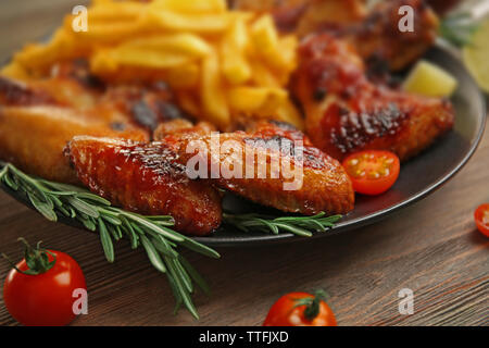 Gegrillte Chicken Wings mit Pommes frites, Garten - Personal und Tomaten auf Platte Stockfoto