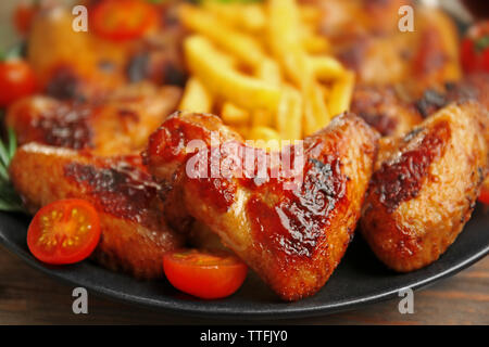 Gegrillte Chicken Wings mit Pommes frites, Garten - Personal und Tomaten auf Platte Stockfoto