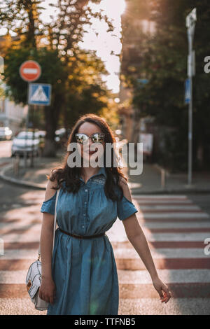 Junge Frau Sonnenbrille tragen beim Überqueren der Straße in der Stadt Stockfoto