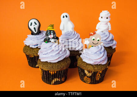 Gruppe von lustigen Halloween Monster Cupcakes auf eine orange Tabelle Stockfoto