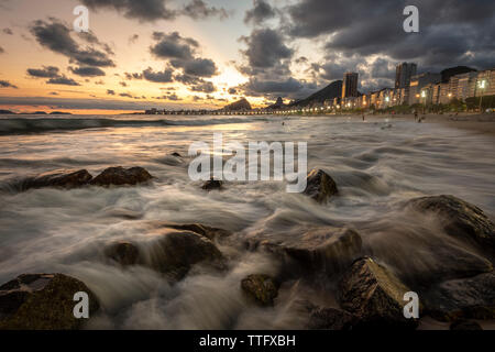 Schönen Sonnenuntergang Landschaft mit Wolken und Wellen auf die Felsen Stockfoto