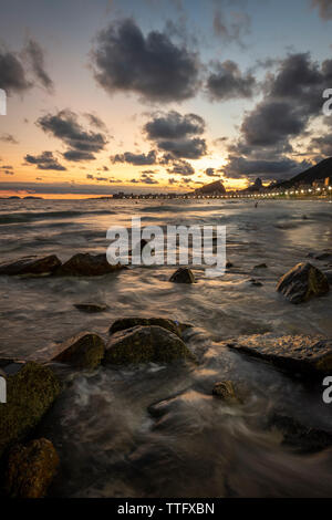 Schönen Sonnenuntergang Landschaft mit Wolken und Wellen auf die Felsen Stockfoto