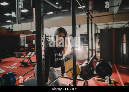 Passform, attraktive Frauen, die das Arbeiten mit einer Langhantel und Squat Rack Stockfoto