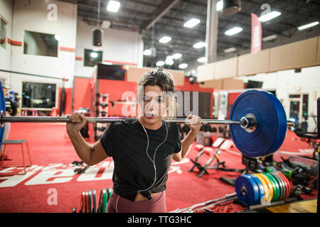 Frau mit Langhantelstange mit Hantelscheiben in Fitnesscenter Stockfoto