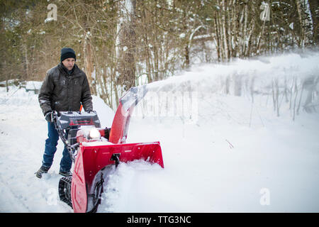 Pensionierter Mann verwendet eine Schneefräse seine Fahrstraße zu löschen. Stockfoto