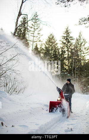 Mann mit Schneefräse Maschine in schneereichen Region im Winter Stockfoto