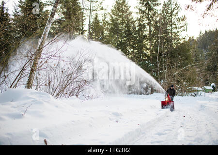 Active Senior Mann mit Schneefräse Maschine zu löschen Auffahrt Stockfoto