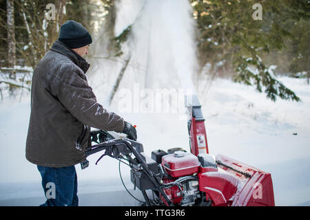 Seitenansicht des Menschen mit Schneefräse Maschine zu löschen Auffahrt Stockfoto