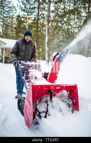 Gesunde ältere zog sich Mann mit Schneefräse Maschine zu löschen Auffahrt Stockfoto