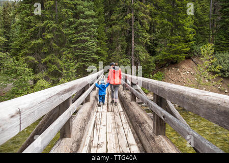 Mutter und Sohn Wanderung über eine hölzerne Brücke in Manning Provincial Park. Stockfoto