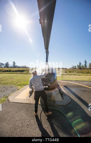 Pilot pflegt und wäscht seinen Hubschrauber nach einem Tag des Fliegens, Stockfoto