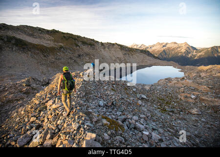 Zwei Rucksacktouristen Ansatz einer alpinen Tarn, British Columbia, Kanada Stockfoto