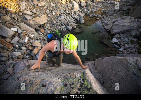 Hohen Winkel des Menschen Bouldern über kleine alpine Tarn. Stockfoto