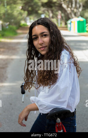 Portrait der Frau mit dem Fahrrad auf der Straße Stockfoto