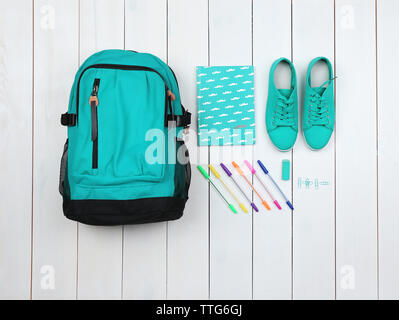 Rucksack und Schulmaterial auf hölzernen Hintergrund, aus der Nähe. Ansicht von oben. Stockfoto