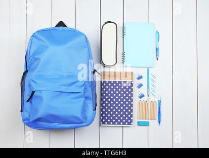 Rucksack und Schulmaterial auf hölzernen Hintergrund, aus der Nähe. Ansicht von oben. Stockfoto