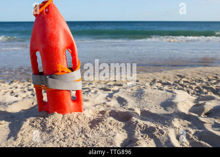 Orange Rescue Buoy auf Sand Strand gepflanzt. Meer Webt als Hintergrund Stockfoto