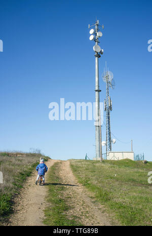 Junge auf Fahrrad per Handy Turm Stockfoto