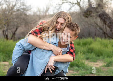 Western Wear junges Paar, piggy fahren Sie zurück und Lachen Stockfoto