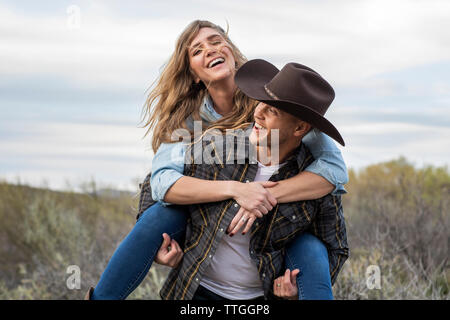 Western Wear junges Paar, piggy fahren Sie zurück und Lachen Stockfoto