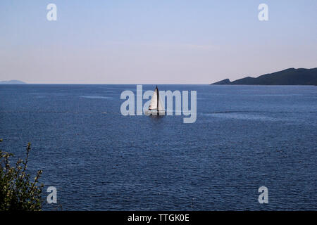 Einsames Schiff, Segelboot auf offener See. Ruhiges Meer ermöglicht beste Segeln in friedliche Szene. Kleines Segelboot auf das türkisfarbene Meer. Schöne Aussicht. Stockfoto