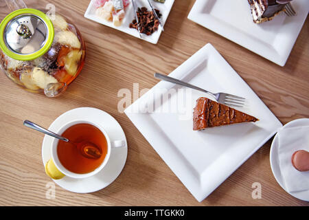 Leckere Kuchen und Tassen Tee auf dem Tisch im Café oder Restaurant Stockfoto
