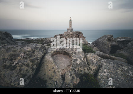 Punta Nariga Leuchtturm an der Küste gegen Himmel und Meer bei Sonnenaufgang Stockfoto